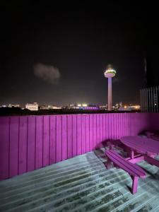a purple wall with a picnic table and a water tower at Penthouse Apartment, Sleeps 21 with terrace in Liverpool