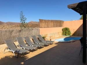a group of chairs sitting next to a swimming pool at Casa Acebuche in La Oliva