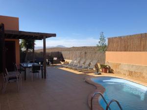 a patio with chairs and a table and a pool at Casa Acebuche in La Oliva