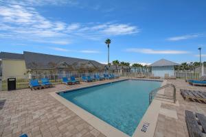 a swimming pool with blue chairs and a fence at Travelodge by Wyndham Panama City Beach / Beachfront in Panama City Beach