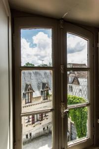 une fenêtre ouverte avec vue sur un bâtiment dans l'établissement L'hôtel de Panette, charpente historique, à Bourges