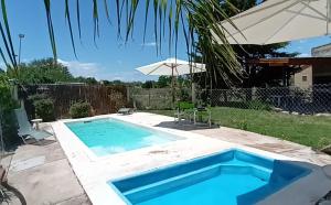a swimming pool in a yard with an umbrella at Cabanas Valle Azul in Villa Rumipal
