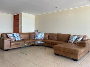 uma sala de estar com um sofá castanho e uma mesa de centro em UMDLOTI - On the BEACH! Private & Central. Sleeps 8. em Umdloti