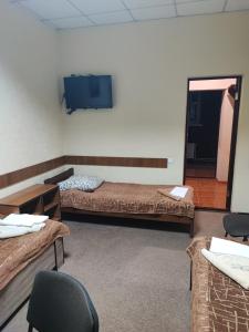 a room with two beds and a flat screen tv at Мотель ОК in Shepetivka