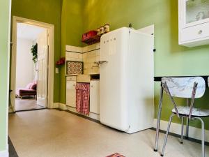 una nevera blanca en una cocina con paredes verdes en De Oude Pastorie, en Bunschoten