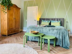 een slaapkamer met een bed en twee groene tafels bij De Oude Pastorie in Bunschoten