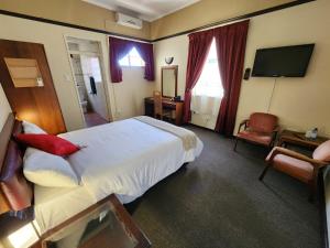Habitación de hotel con cama grande y TV en Royal Hotel Ladysmith, en Ladysmith