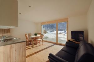 ein Wohnzimmer mit einem Sofa und eine Küche mit einem Tisch in der Unterkunft Châlet Bärgfride in Kandersteg