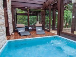 a house with a swimming pool and two chairs at Pousada Jardim das Montanhas in Monte Verde