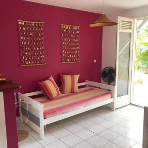 Cette chambre est dotée de murs violets et d'un banc avec des oreillers. dans l'établissement résidence Kaz'Tinou - Allo Sé Ann, à Saint-François