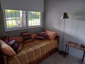 Habitación con sofá con almohadas y ventana. en Casa Quinta Roen Gral Rodriguez zona oeste en General Rodríguez
