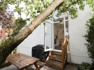 a tree leaning over a house with a wooden bench at North View Cottage next to Hadrian's Wall in Gilsland