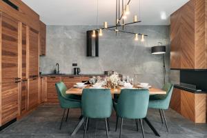 a dining room with a wooden table and green chairs at Polana Resort by LoftAffair in Kościelisko