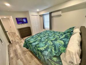 a bedroom with a bed with a green comforter and a tv at Sleeps 22, 7 bedrooms, 2min walk To The Beach, Private Heated Pool and Hot Tub, Zula Del Mar South Padre Island Texas in South Padre Island