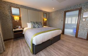 a hotel room with a bed and a bathroom at The Valley Hotel & Carriage Gardens in Fivemiletown