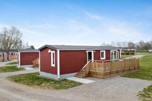 um pequeno edifício vermelho com um alpendre e uma casa em First Camp Karlstorp-Halmstad em Halmstad