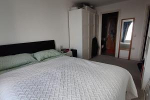 1 dormitorio con 1 cama grande y edredón blanco en Cosy and spacious apartment in Forest Hill en Forest Hill