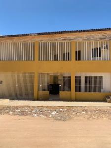 un edificio blanco y amarillo con puertas y ventanas en Aconchego da Mary, en Maragogi