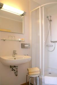 a white bathroom with a sink and a shower at Baltic Kölln Hotel in Heiligenhafen