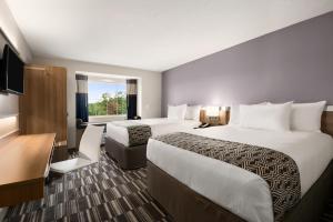 a hotel room with two beds and a desk at Microtel Inn & Suites by Wyndham in Lynchburg +26 photos