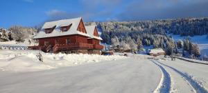 una casa cubierta de nieve junto a una carretera en Privat Bachledova dolina, en Ždiar