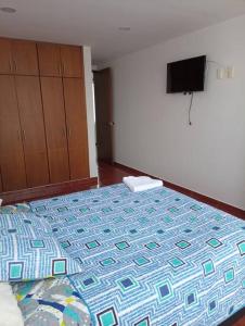 1 dormitorio con 1 cama y TV en la pared en Agradable Casa Familiar con parqueadero privado, en Paipa