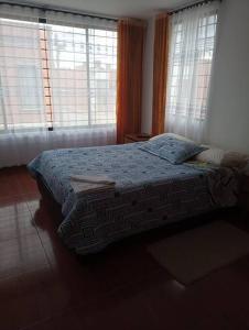 1 dormitorio con 1 cama y 2 ventanas en Agradable Casa Familiar con parqueadero privado, en Paipa