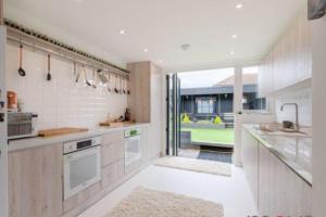 Down HatherleyにあるModern 4 bed home, hottub and traditional pubの白い家電製品付きのキッチン、大きな窓