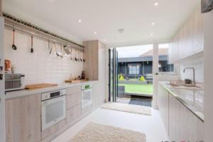 a kitchen with white appliances and a large window at Modern 4 bed home, hottub and traditional pub in Down Hatherley