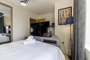 um quarto com uma cama branca e uma televisão em Remarkable 4-Bedroom 3-Bathroom House em Pontefract