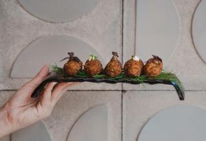 a person holding a branch with birds on it at Kimpton Aysla Mallorca by IHG in Santa Ponsa