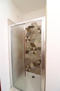 Una ducha con puerta de cristal y pared de azulejos. en CASA ANGELA, en Castiglion Fiorentino