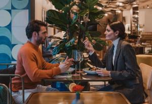 a man and woman sitting at a table in a restaurant at Kimpton Aysla Mallorca by IHG in Santa Ponsa
