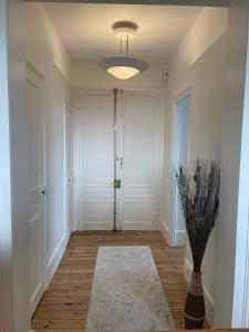 un couloir avec une porte blanche et un vase dans l'établissement Le Royal XIX Vue mer, à Dinard