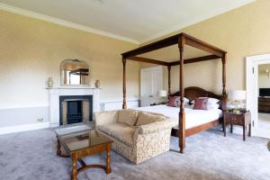 1 dormitorio con cama con dosel y chimenea en Balbirnie House Hotel, en Glenrothes