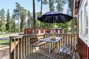einen Picknicktisch mit einem Sonnenschirm auf dem Deck in der Unterkunft First Camp Kolmården-Norrköping in Kolmården