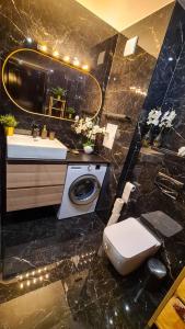 La salle de bains est pourvue de toilettes, d'un lavabo et d'un miroir. dans l'établissement Apartmanica Double room apartment with balcony, St Ivan Rilski 4 star SPA Resort, Bansko, à Bansko