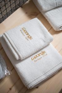 dos toallas blancas con escritura de oro en una mesa en George Boutique Hotel, en Voskopojë