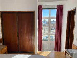 1 dormitorio con cama y ventana grande en Residencial Arabi en Portimão