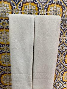 dos toallas blancas colgando en una pared en Residencial Arabi, en Portimão