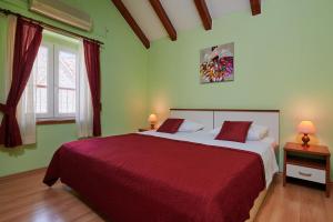 a bedroom with a large bed with a red blanket at Apartments Ivica in Trogir