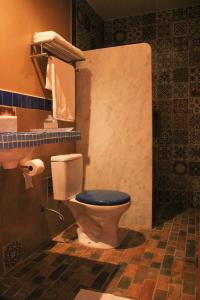 a bathroom with a toilet with a blue seat at Pousada No Meio do Mundo in Anchieta