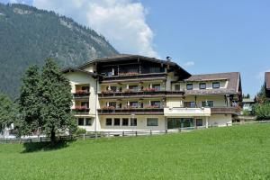 een groot gebouw op een heuvel met een groen veld bij Hotel Waldheim Garni in Mayrhofen