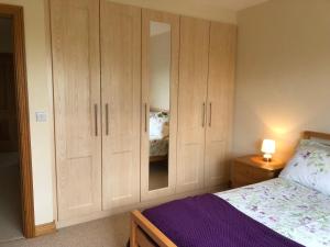 a bedroom with wooden cabinets and a bed at Slemish View - a beautiful setting in countryside in Ballymena