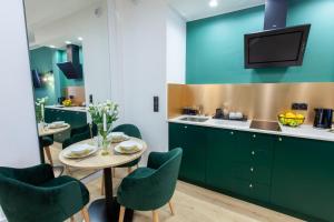 a kitchen with green cabinets and a table and chairs at SQUARE APARTMENTS GDYNIA in Gdynia