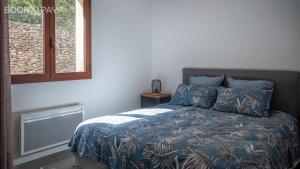 a bedroom with a bed with a blue blanket and a window at Villa Colombo in Bonifacio