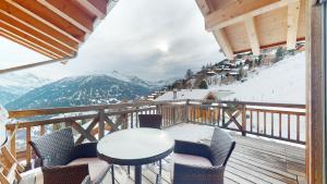 a balcony with a table and chairs and mountains at Etoiles des Neiges LUXE & JACUZZI chalet 12 pers by Alpvision Résidences in Hérémence