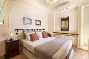 1 dormitorio con 1 cama grande con sábanas blancas y almohadas de color naranja en Seaview Beach House, en Ándros