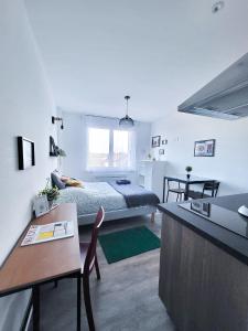 a bedroom with a bed and a table and a kitchen at LA MASCOTTE in Saint-Louis