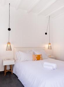 a white bedroom with a white bed with two lamps at Nautilus Serifos in Livadakia